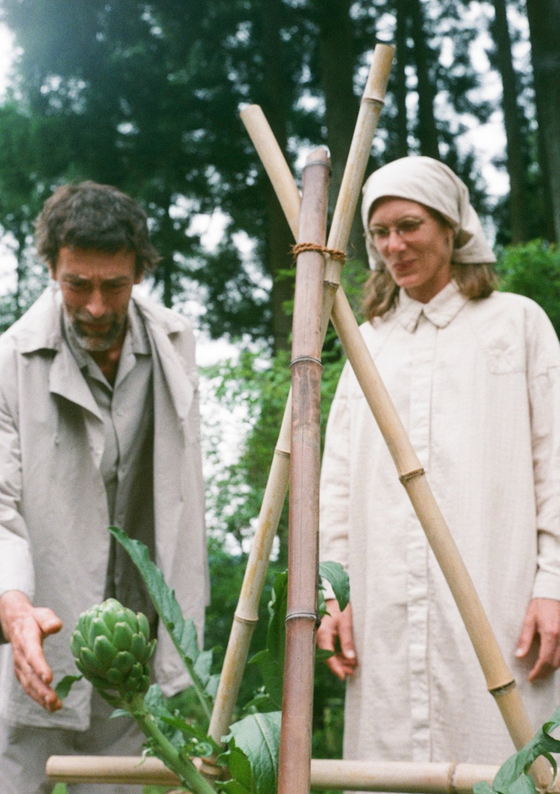 Sébastien and Mélanie look at artichokes at harvest time. Mélanie wears an organic cotton double-gauze check citron ash-colored country shirt dress and hair accessories